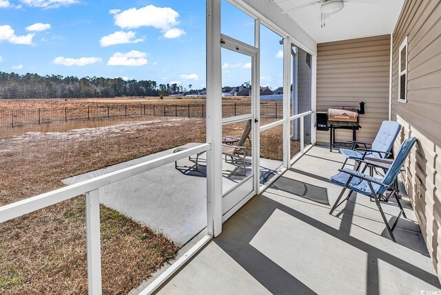 sunroom featuring a rural view and ceiling fan