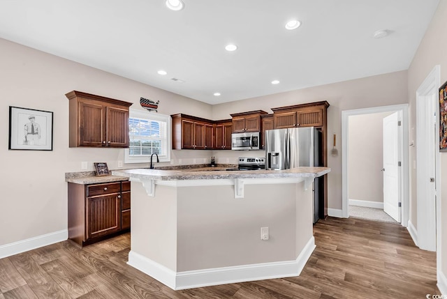 kitchen featuring sink, a center island, light hardwood / wood-style flooring, a kitchen breakfast bar, and stainless steel appliances