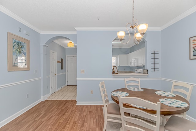 dining space featuring crown molding, light hardwood / wood-style floors, a chandelier, and a textured ceiling