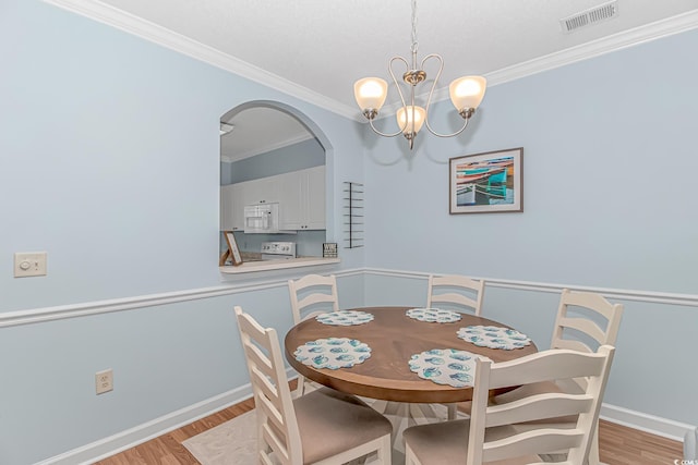 dining room with crown molding, an inviting chandelier, and light wood-type flooring