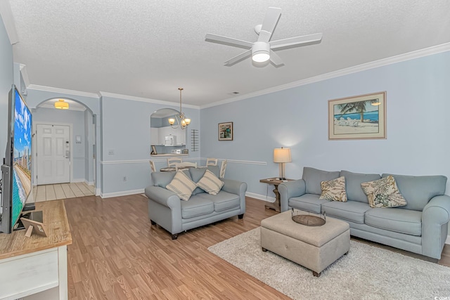 living room with hardwood / wood-style flooring, ornamental molding, ceiling fan with notable chandelier, and a textured ceiling