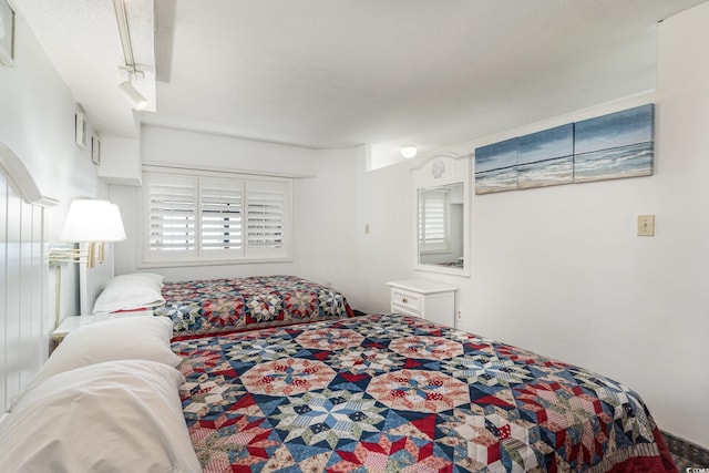 bedroom featuring track lighting and a textured ceiling