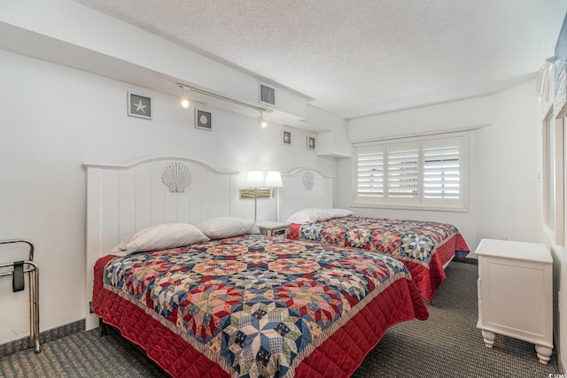 bedroom with a textured ceiling and dark colored carpet