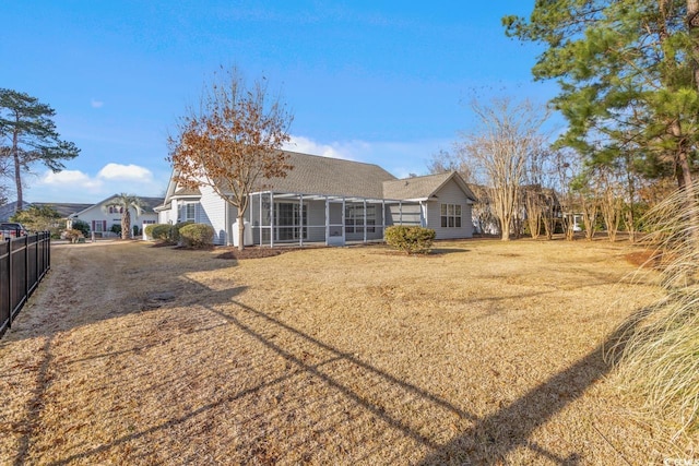 back of property with a sunroom and a lawn