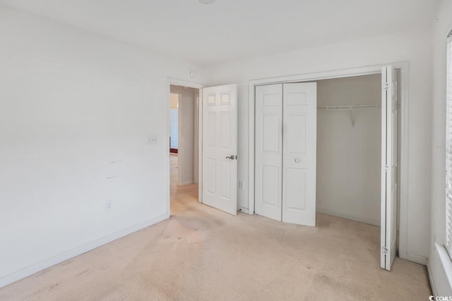 unfurnished bedroom with light colored carpet and a closet