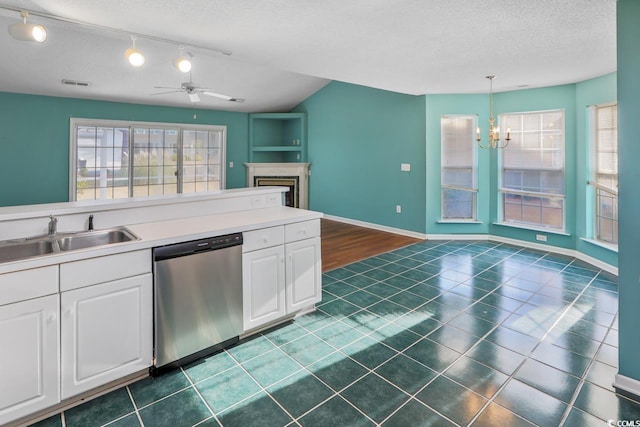 kitchen featuring sink, white cabinets, hanging light fixtures, stainless steel dishwasher, and a textured ceiling