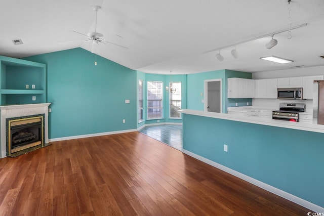 kitchen featuring ceiling fan, appliances with stainless steel finishes, wood-type flooring, white cabinets, and vaulted ceiling