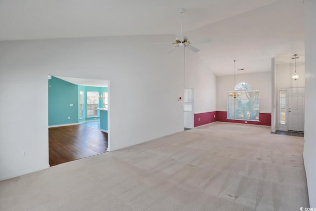 unfurnished living room with high vaulted ceiling, light colored carpet, and ceiling fan