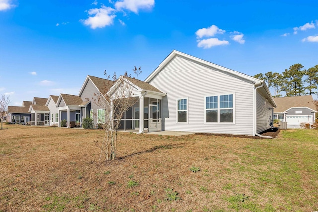 rear view of property with a patio, a yard, and a sunroom