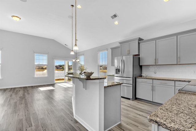 kitchen with gray cabinets, dark stone counters, hanging light fixtures, a center island, and stainless steel refrigerator with ice dispenser