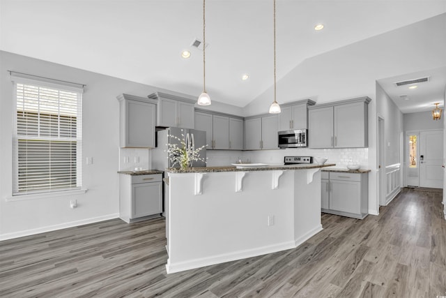 kitchen with gray cabinetry, stainless steel appliances, a kitchen breakfast bar, and a kitchen island