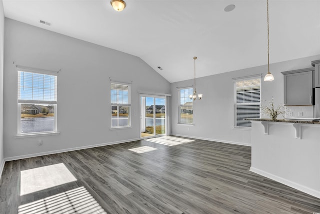 unfurnished living room featuring lofted ceiling, dark hardwood / wood-style flooring, and a chandelier