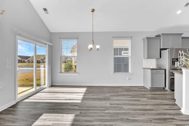 unfurnished dining area with an inviting chandelier, lofted ceiling, and hardwood / wood-style floors