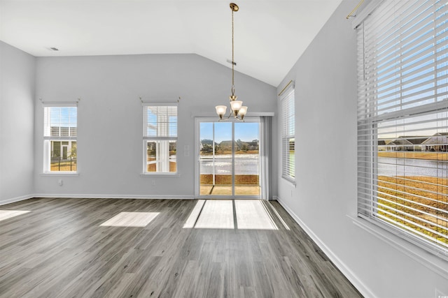 unfurnished dining area with wood-type flooring, lofted ceiling, and an inviting chandelier