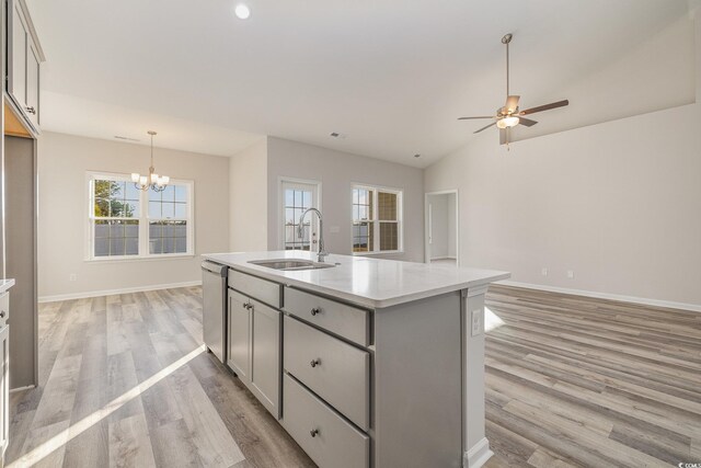 kitchen with dishwasher, sink, gray cabinetry, hanging light fixtures, and a center island with sink