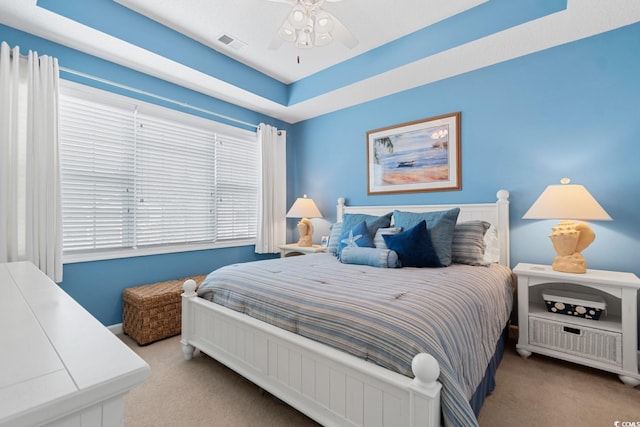 bedroom with visible vents, carpet flooring, a raised ceiling, and ceiling fan