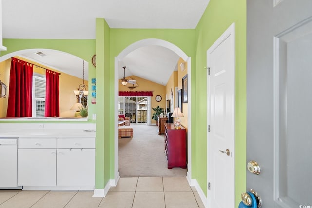 corridor with vaulted ceiling, light tile patterned floors, baseboards, and light carpet