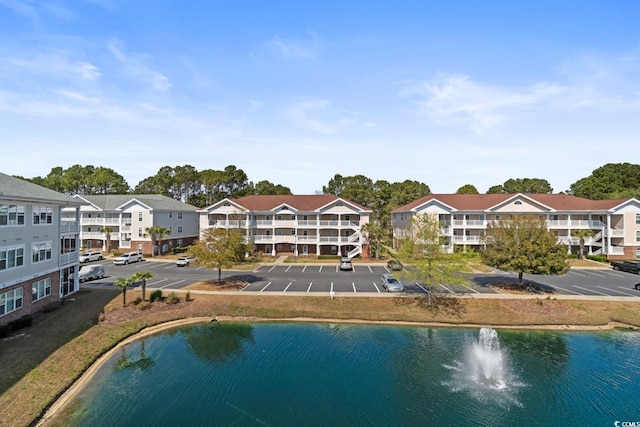 back of house featuring uncovered parking and a water view