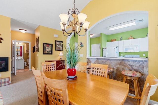 dining area featuring visible vents, carpet, arched walkways, and a chandelier