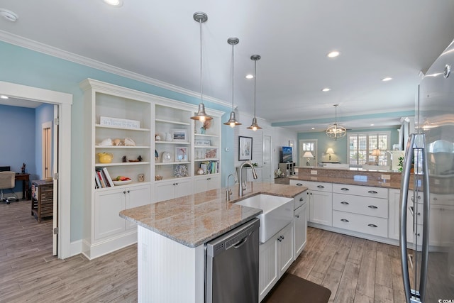 kitchen featuring sink, appliances with stainless steel finishes, pendant lighting, a kitchen island with sink, and white cabinets