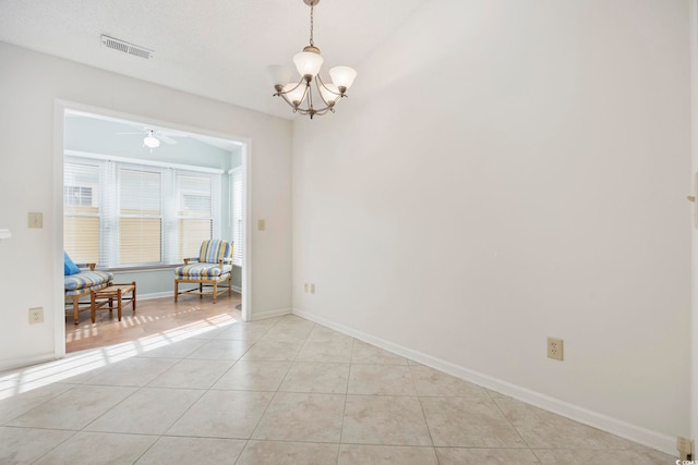 tiled empty room with ceiling fan with notable chandelier