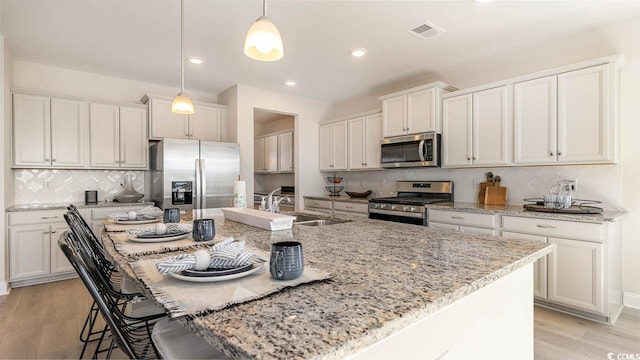 551 Slaty Dr, Myrtle Beach, SC 29588 - kitchen featuring appliances with stainless steel finishes, a sink, a kitchen island with sink, backsplash, and a breakfast bar area