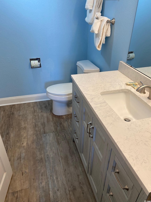 bathroom with hardwood / wood-style flooring, vanity, and toilet