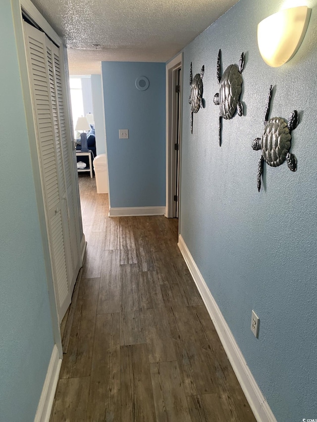 hallway featuring dark wood-type flooring and a textured ceiling