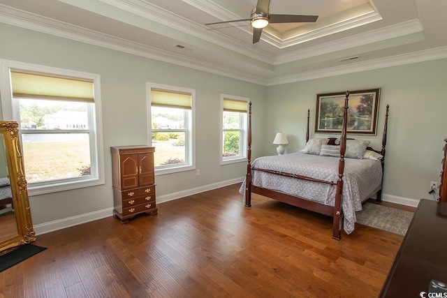 bedroom featuring dark wood-type flooring, ceiling fan, a tray ceiling, and crown molding