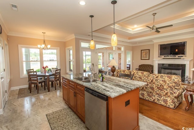 kitchen featuring sink, light stone counters, dishwasher, pendant lighting, and a kitchen island with sink