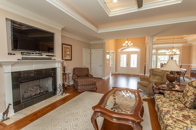 living room featuring an inviting chandelier, light hardwood / wood-style flooring, ornamental molding, and a raised ceiling