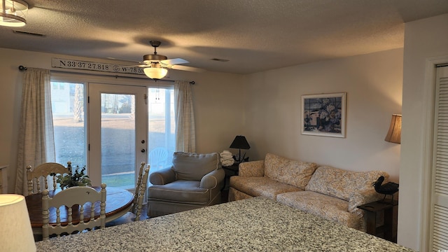 living room with ceiling fan and a textured ceiling