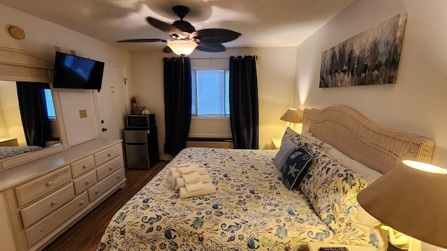 bedroom with dark wood-type flooring, black refrigerator, and ceiling fan