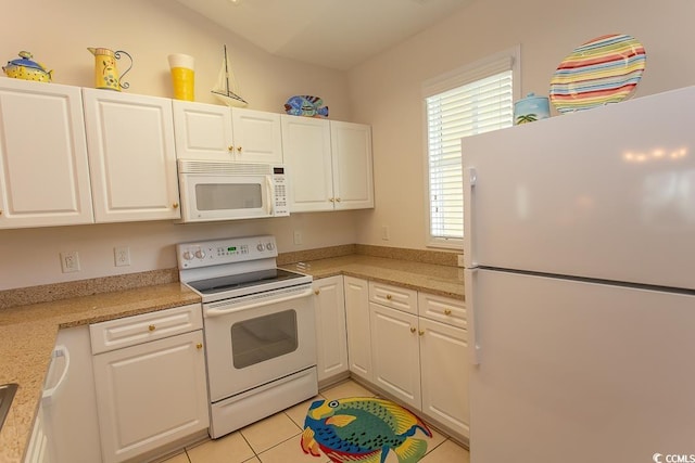 kitchen with light tile patterned flooring, light stone countertops, white cabinets, and white appliances