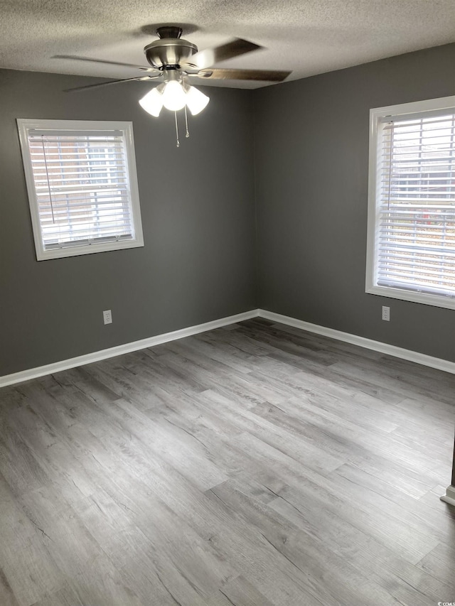 unfurnished room featuring ceiling fan, a textured ceiling, baseboards, and wood finished floors