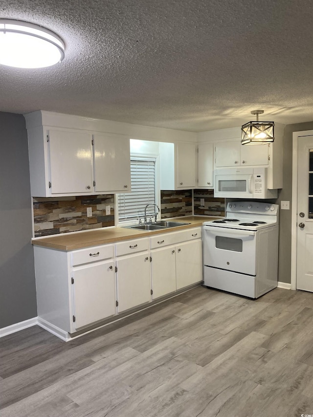 kitchen with white appliances, light wood-style flooring, tasteful backsplash, and a sink