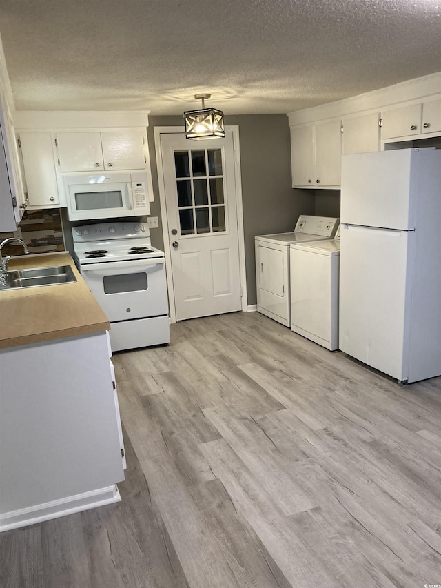 kitchen featuring washing machine and dryer, white appliances, white cabinets, and a sink