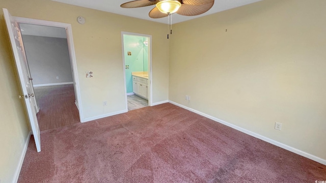 unfurnished bedroom with ensuite bath, light colored carpet, and ceiling fan