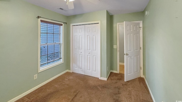 unfurnished bedroom with ceiling fan, carpet flooring, a closet, and a textured ceiling