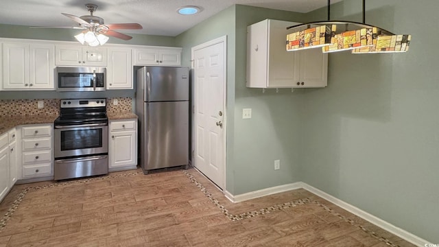 kitchen featuring white cabinetry, stainless steel appliances, decorative light fixtures, and light hardwood / wood-style flooring