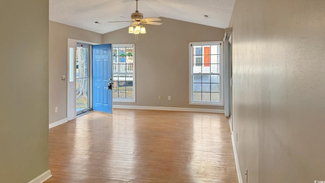 spare room featuring plenty of natural light, vaulted ceiling, light hardwood / wood-style flooring, and a textured ceiling