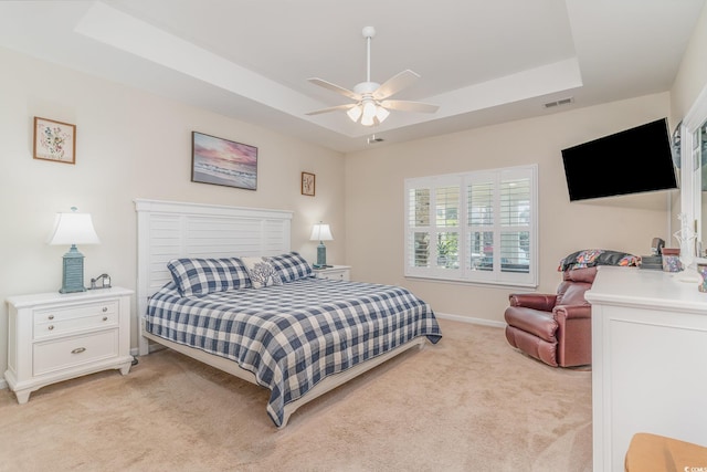 bedroom featuring ceiling fan, a raised ceiling, and light carpet