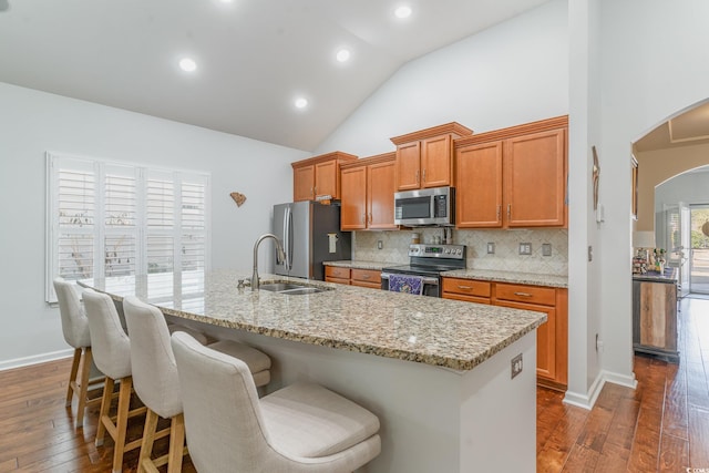 kitchen with dark hardwood / wood-style floors, an island with sink, sink, backsplash, and stainless steel appliances