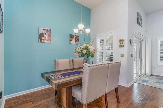 dining space with a notable chandelier, a towering ceiling, and dark wood-type flooring