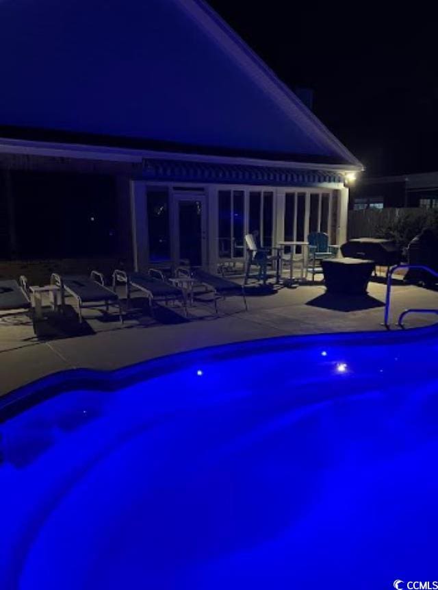 pool at night with a patio area