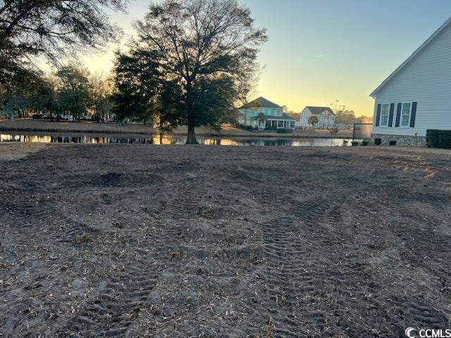 yard at dusk featuring a water view