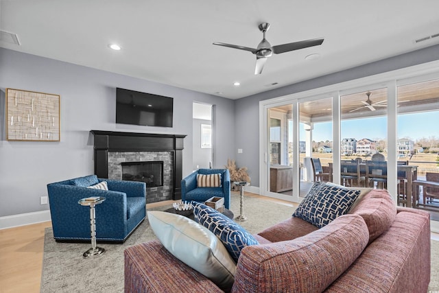 living room with ceiling fan, a fireplace, and light hardwood / wood-style floors