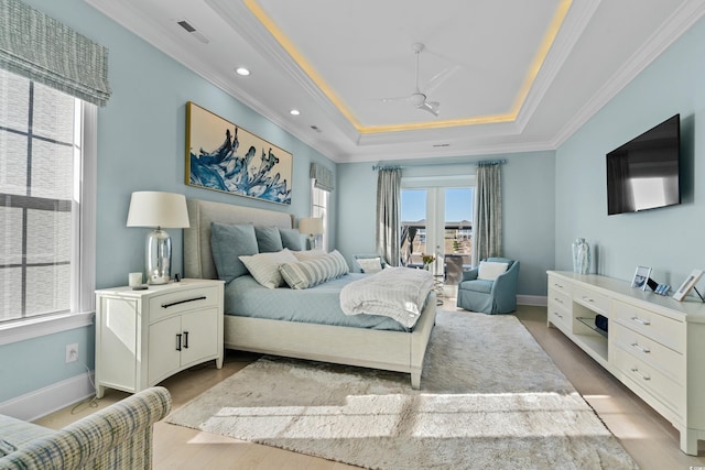 bedroom with ornamental molding, light hardwood / wood-style flooring, and a tray ceiling