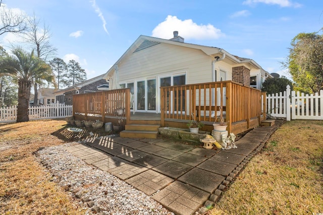 rear view of property with a chimney, fence, and a wooden deck