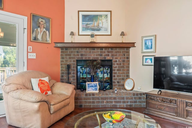 living room with a brick fireplace and wood finished floors